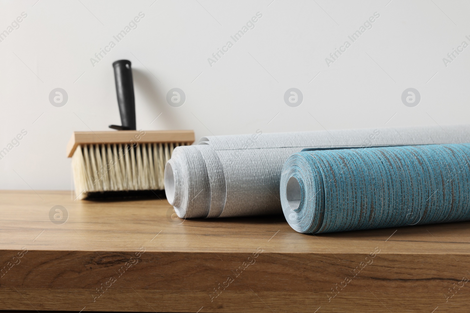 Photo of Wallpaper rolls and brush on wooden table