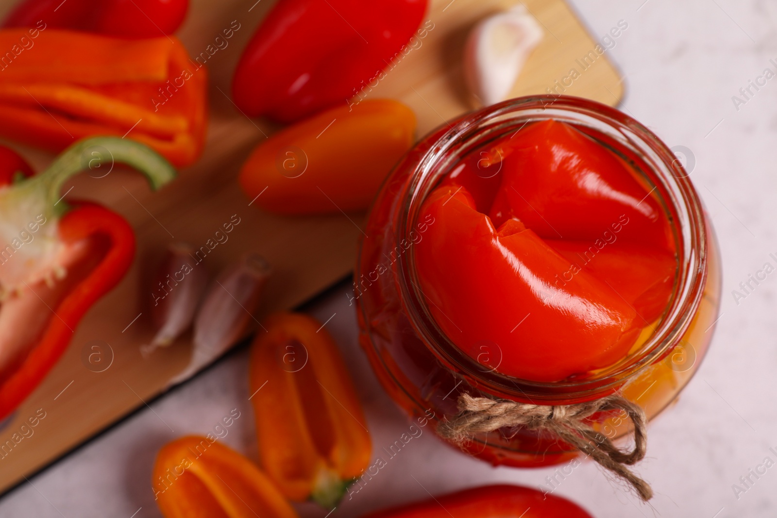 Photo of Jar with tasty pickled peppers and fresh vegetables on table, closeup. Space for text