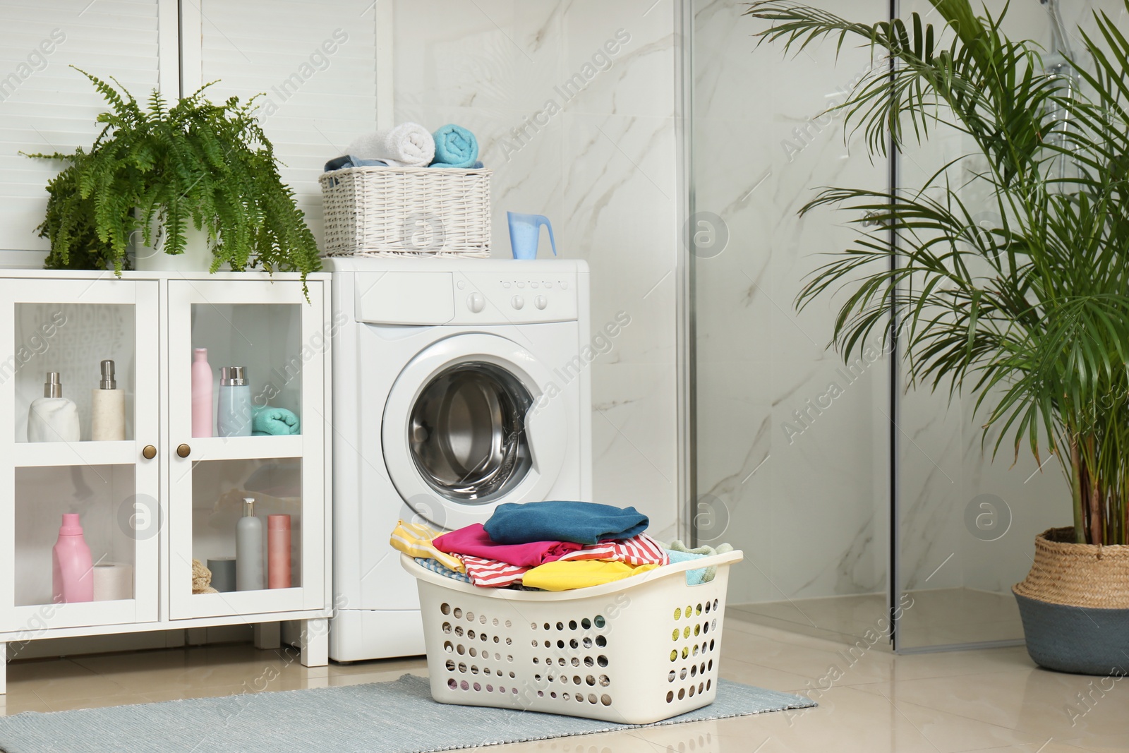 Photo of Basket with laundry and washing machine in bathroom