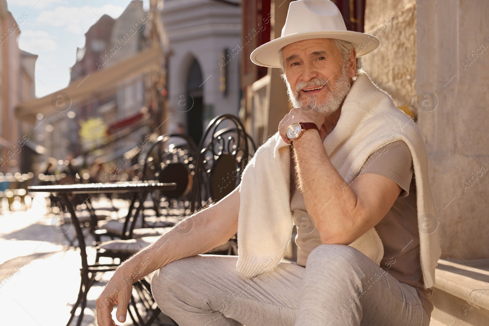 Photo of Handsome senior man sitting on doorstep outdoors, space for text