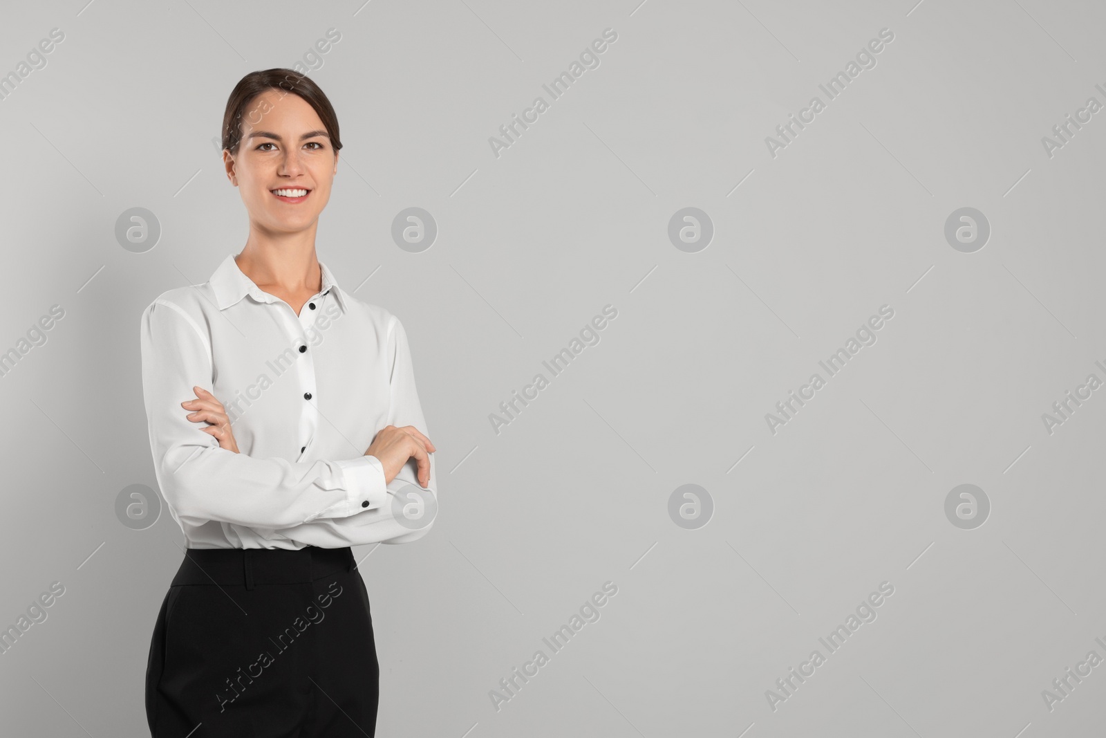 Photo of Happy secretary with crossed arms on light grey background, space for text