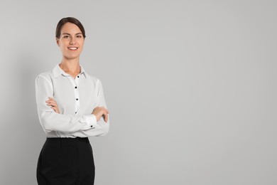 Photo of Happy secretary with crossed arms on light grey background, space for text