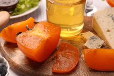 Delicious persimmon, blue cheese and honey on wooden board, closeup