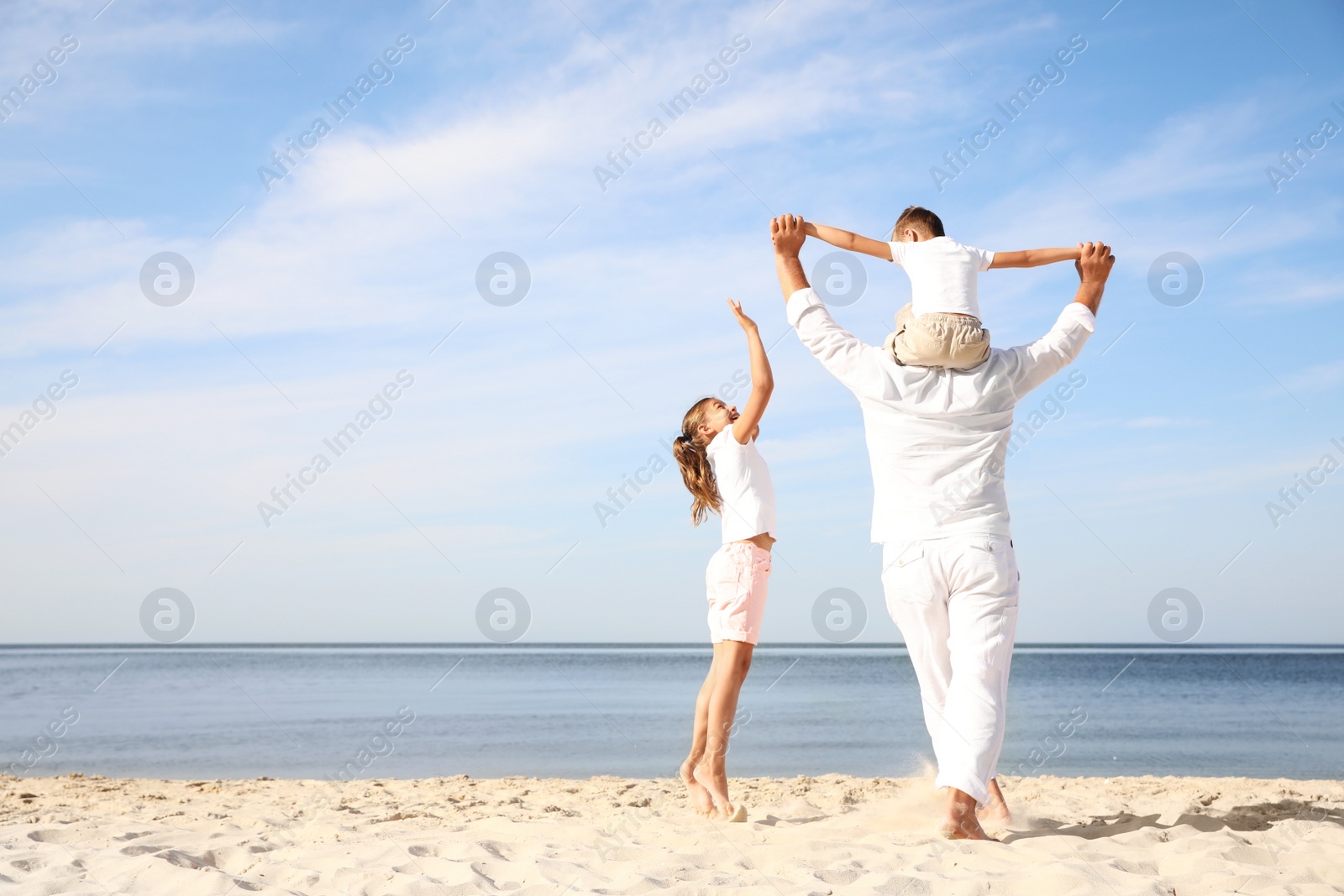 Photo of Cute little children with grandfather spending time together on sea beach