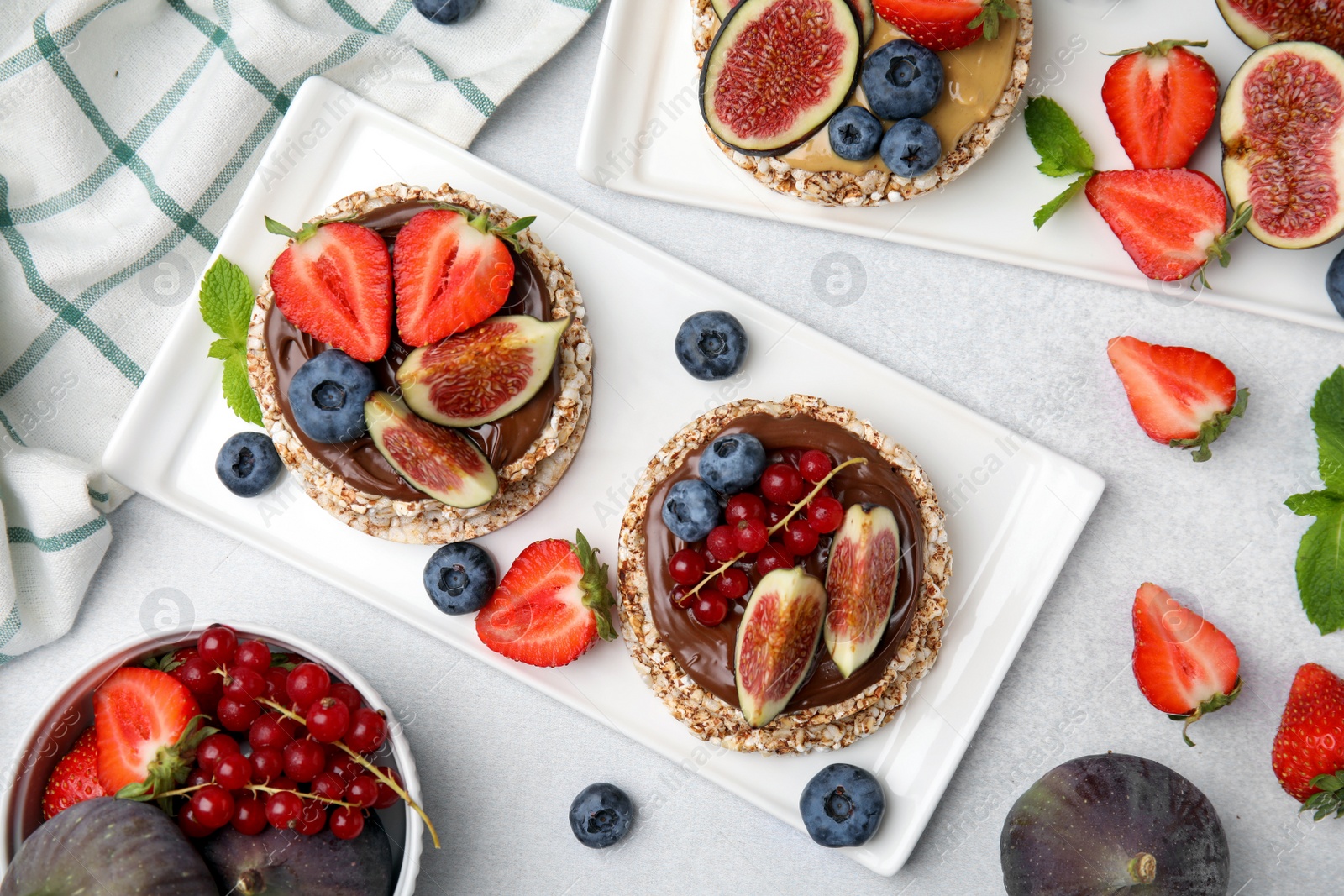 Photo of Tasty crispbreads with different toppings served on light table, flat lay