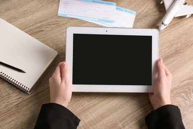 Woman holding tablet with blank screen over table, closeup. Travel agency