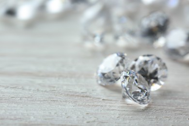 Beautiful shiny diamonds on light wooden table, closeup. Space for text