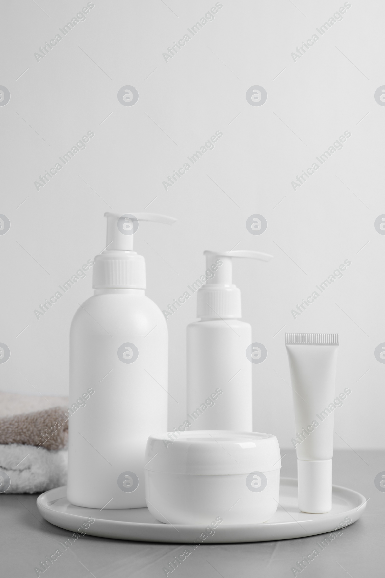 Photo of Different cosmetic products, towels and dry leaves on grey table