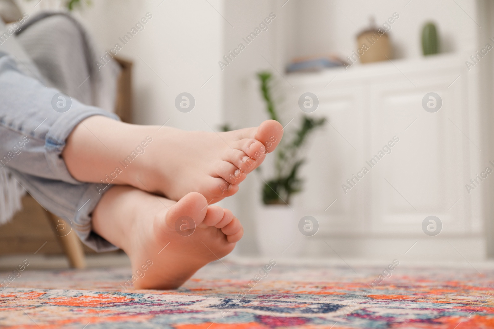 Photo of Woman sitting near carpet with pattern indoors, closeup. Space for text