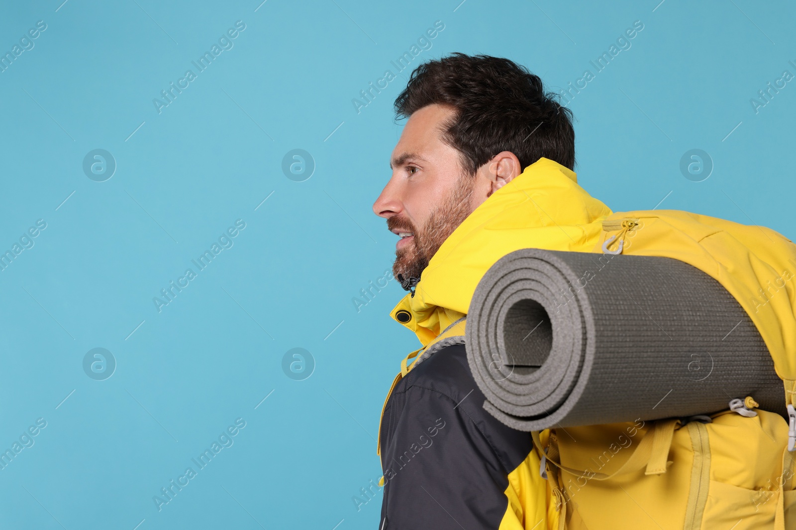 Photo of Man with backpack on light blue background, space for text. Active tourism