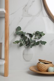 Photo of Silicone vase with eucalyptus branches on white marble wall over countertop in stylish bathroom