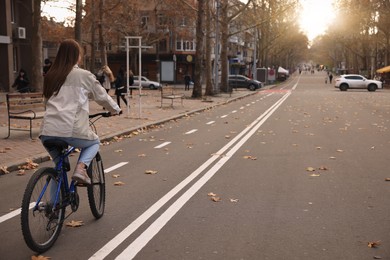 Woman riding bicycle on lane in city