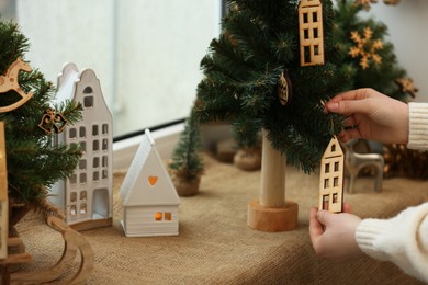 Photo of Woman decorating small Christmas tree on window sill indoors, closeup