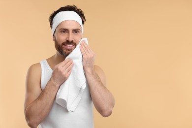 Photo of Washing face. Man with headband and towel on beige background, space for text