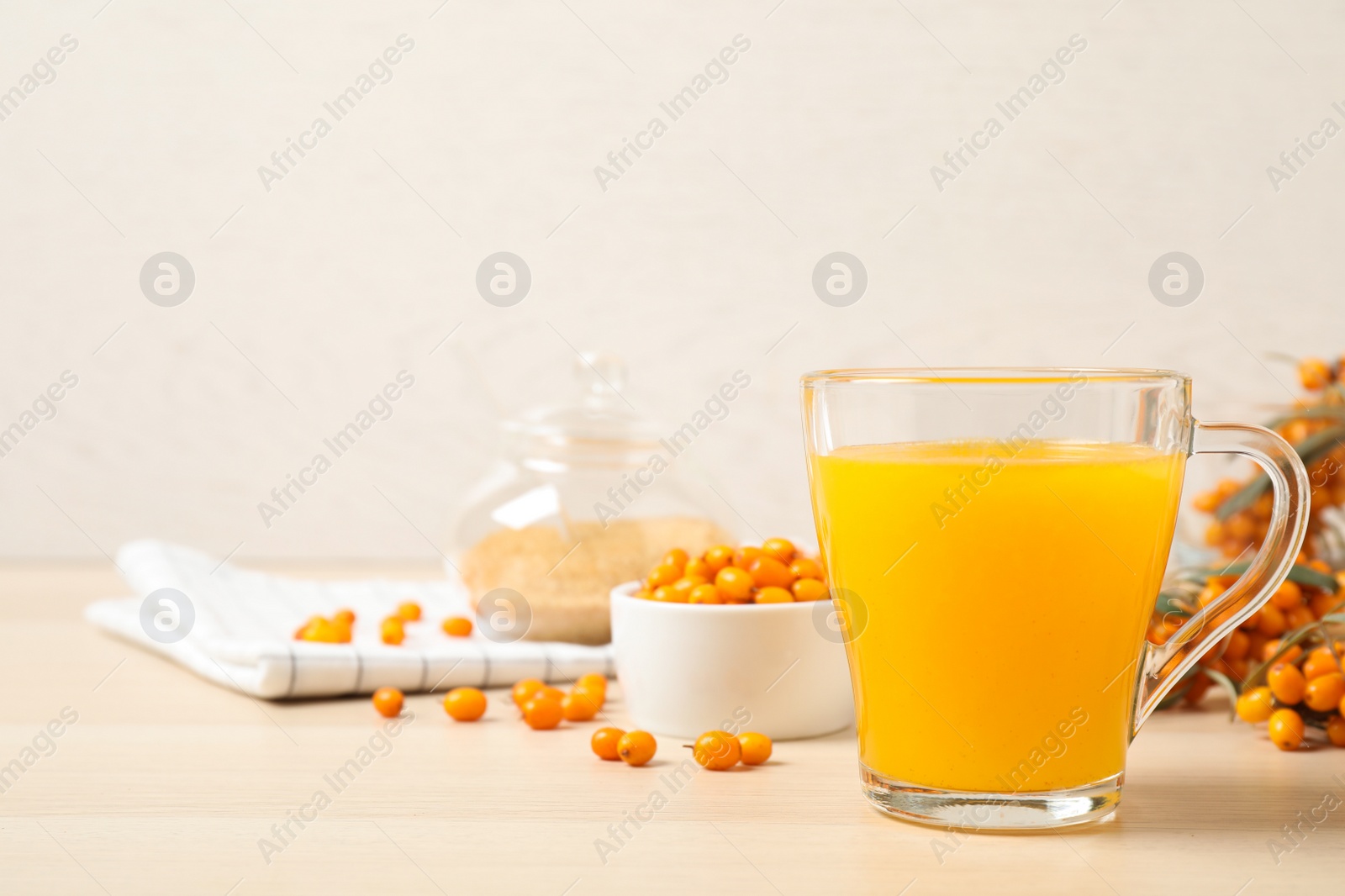 Photo of Delicious sea buckthorn tea and fresh berries on wooden table. Space for text