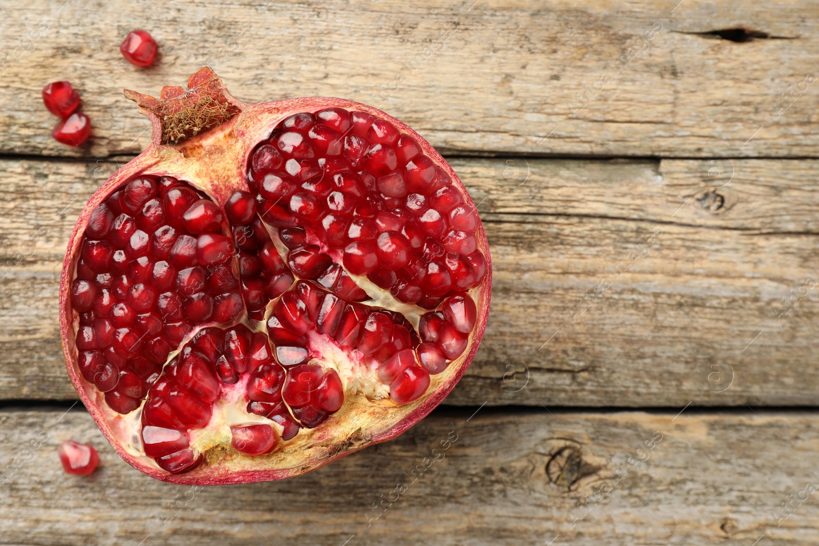 Photo of Cut fresh pomegranate on wooden table, top view. Space for text