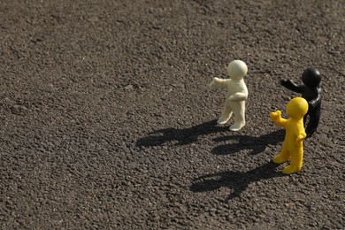 Many plasticine human figures on asphalt road outdoors, space for text