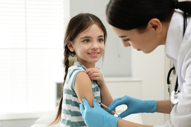 Photo of Doctor vaccinating little child in modern clinic