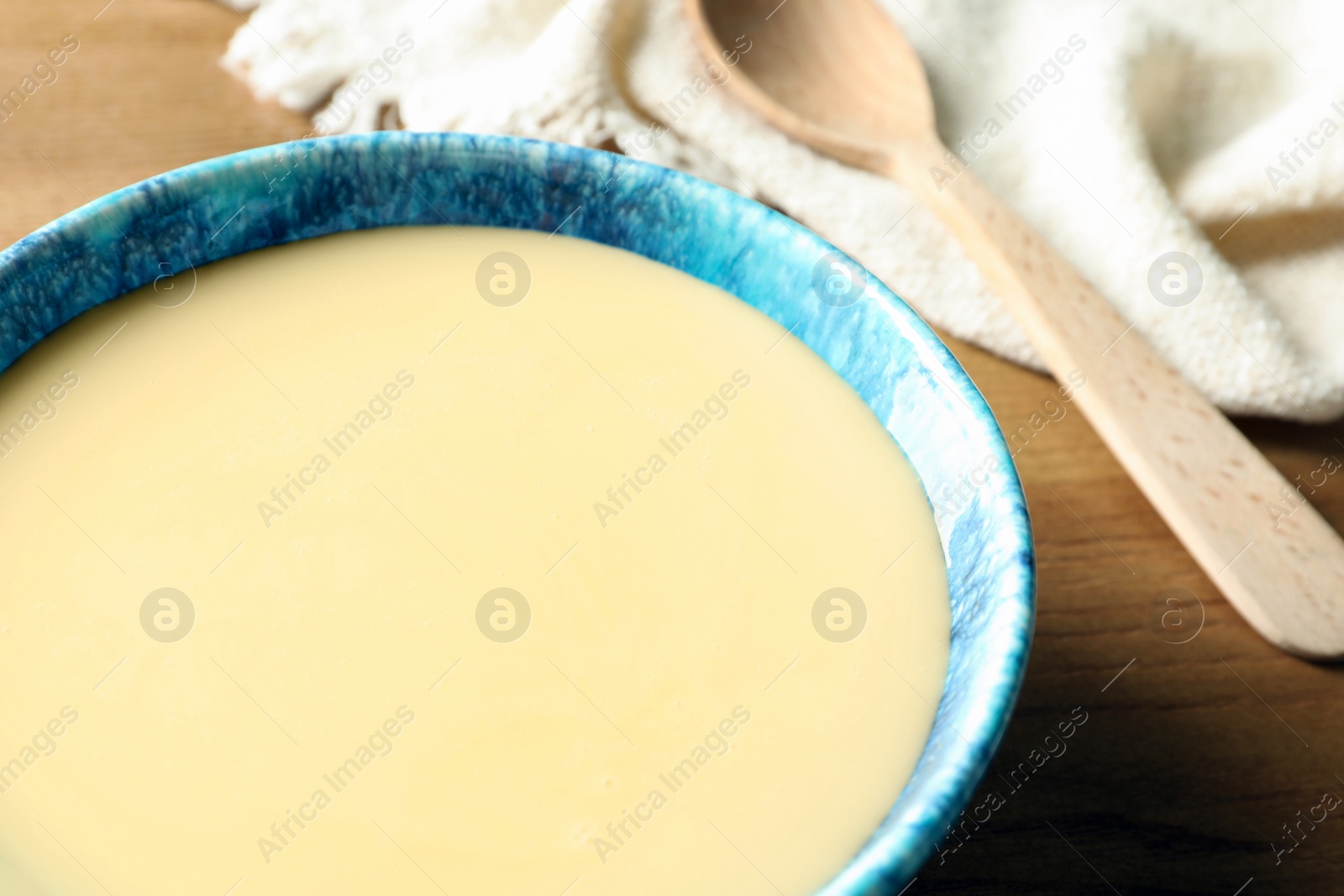 Photo of Bowl with condensed milk on table, closeup. Dairy products