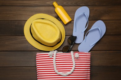 Stylish bag and beach accessories on wooden background, flat lay