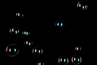 Photo of Beautiful translucent soap bubbles on dark background