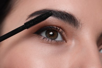 Photo of Beautiful young woman applying mascara, closeup view