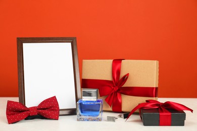 Photo of Happy Father's Day. Empty frame and presents on white table, closeup. Space for text