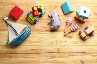 Different toys on wooden background, flat lay. Space for text