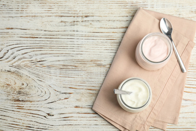 Photo of Tasty organic yogurt on white wooden table, flat lay. Space for text