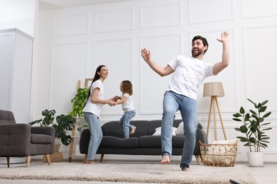 Happy family dancing in living room, low angle view