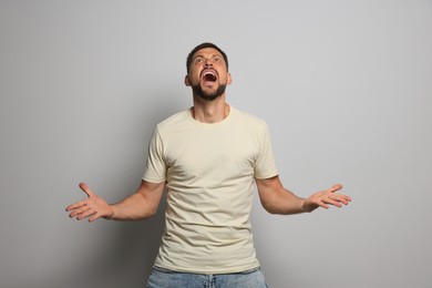 Photo of Aggressive man shouting on grey background. Hate concept