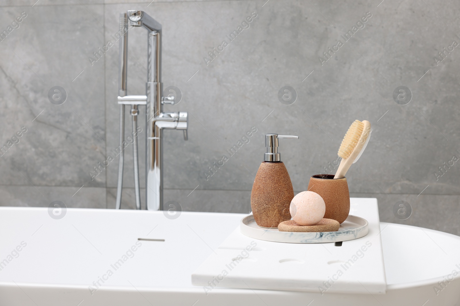 Photo of Different personal care products and accessories on bath tub in bathroom, space for text