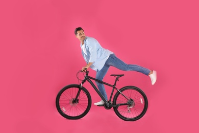 Photo of Handsome young man with modern bicycle on pink background