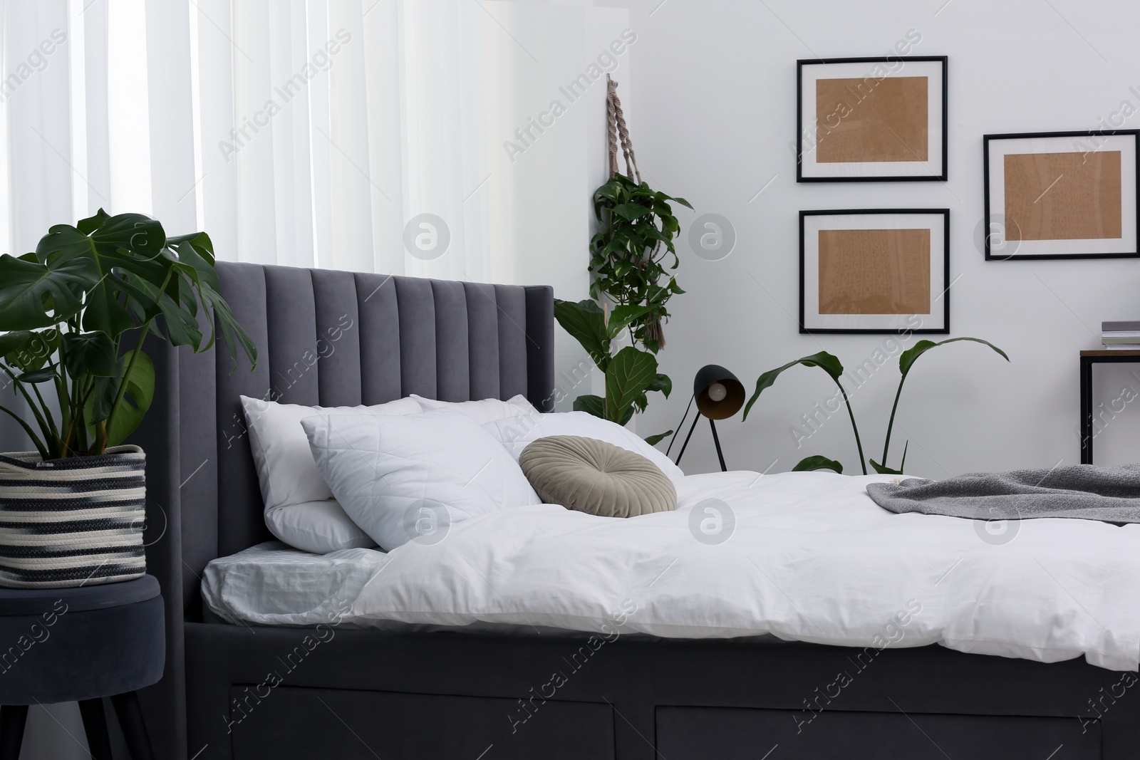 Photo of Large comfortable bed and beautiful houseplants in room. Bedroom interior