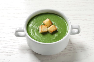 Photo of Fresh vegetable detox soup with croutons in dish on wooden table