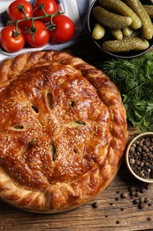 Photo of Tasty homemade pie and ingredients on wooden table, flat lay