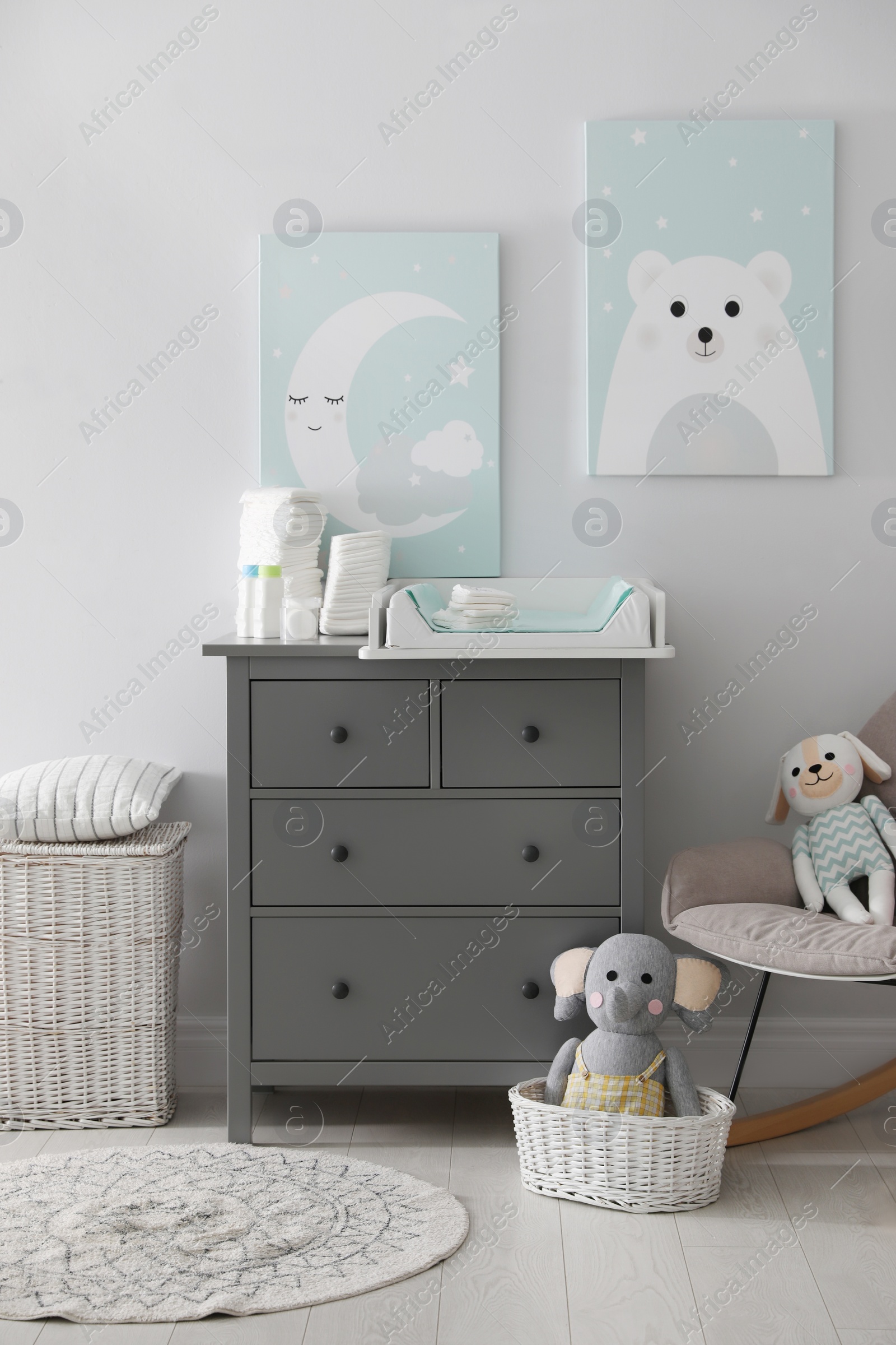 Photo of Chest of drawers with changing tray and pad in baby room. Interior design