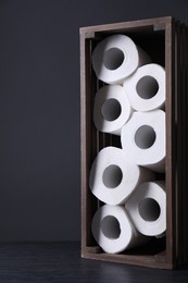 Photo of Toilet paper rolls in crate on wooden table, space for text