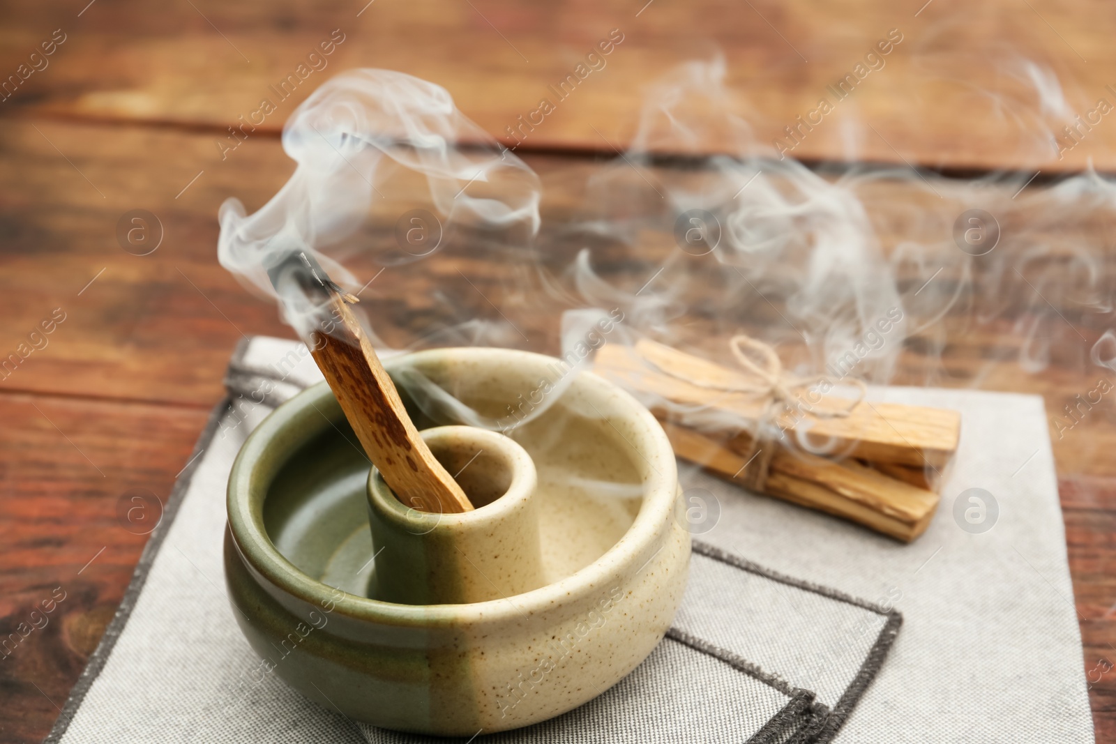 Photo of Palo Santo stick smoldering in holder on wooden table
