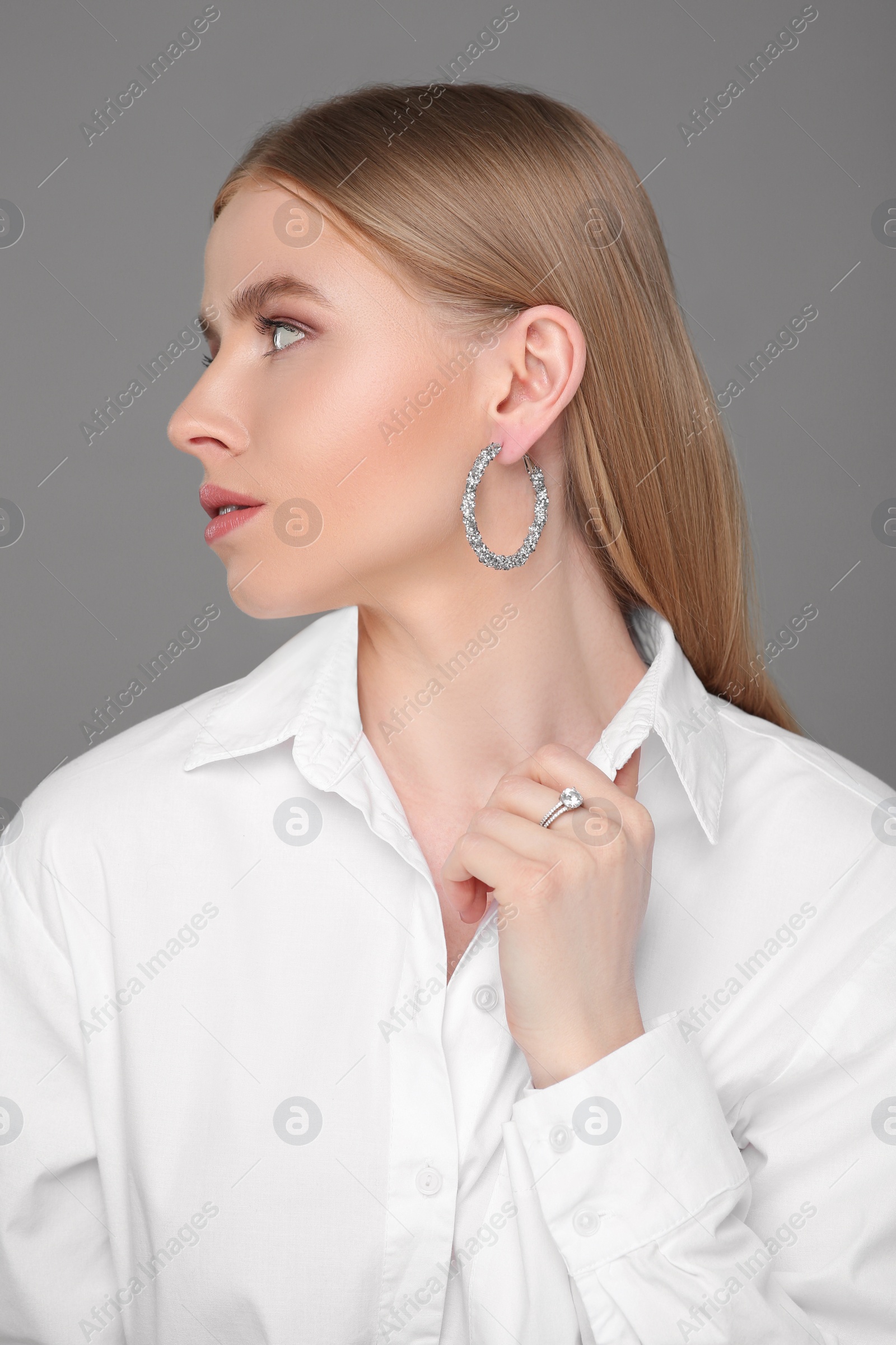 Photo of Beautiful young woman with elegant jewelry on gray background