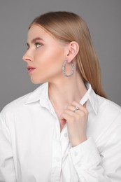 Photo of Beautiful young woman with elegant jewelry on gray background