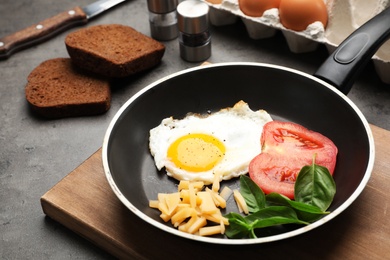 Photo of Pan with fried sunny side up egg, cheese and tomato on table