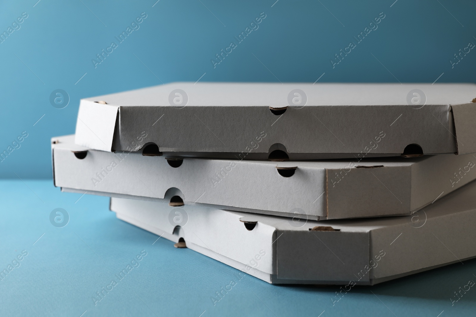 Photo of Stack of empty pizza boxes on light blue background, closeup