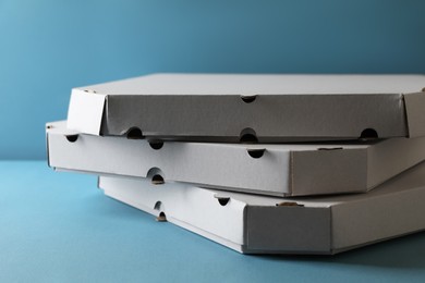 Stack of empty pizza boxes on light blue background, closeup