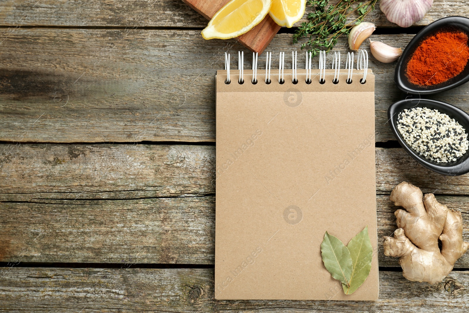 Photo of Blank recipe book and different ingredients on old wooden table, flat lay. Space for text