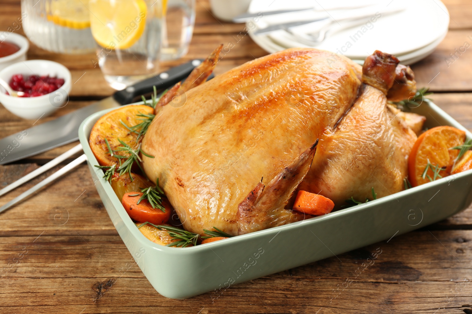 Photo of Roasted chicken with oranges and carrot on wooden table, closeup