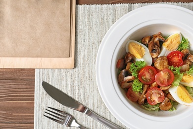 Photo of Plate with delicious fresh salad and menu on table, top view