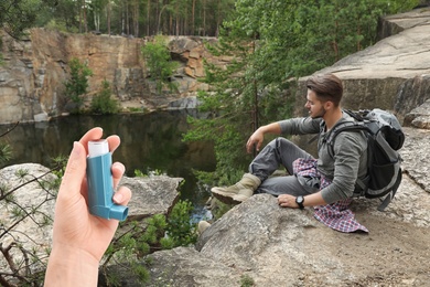 Image of Woman with asthma inhaler and mountain landscape on background, closeup. First emergency medical aid