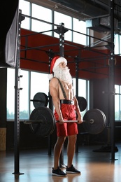 Young muscular man in Santa costume training at gym