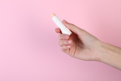 Photo of Woman with lip balm on pink background, closeup
